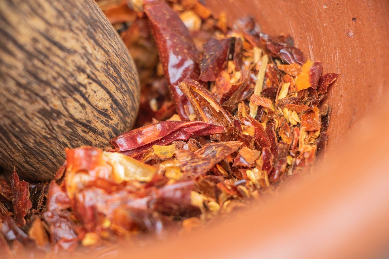 Close-up of crushed red chili peppers in a mortar, showcasing spicy ingredients.